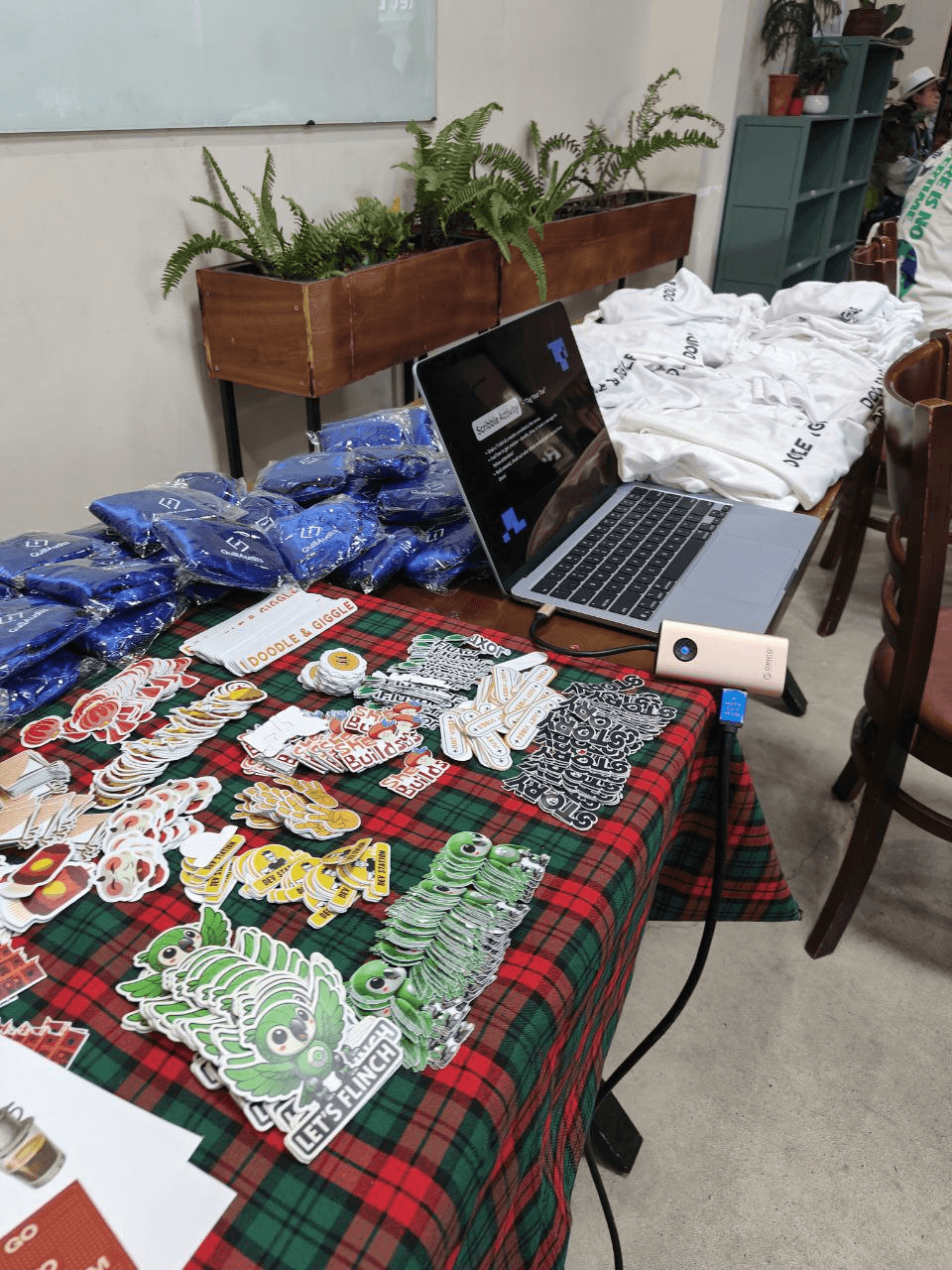 QuillAudits event table displaying a laptop, merchandise, shirts, and stickers