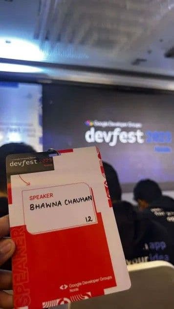 Bhawna's speaker badge held in front of the DevFest Noida stage